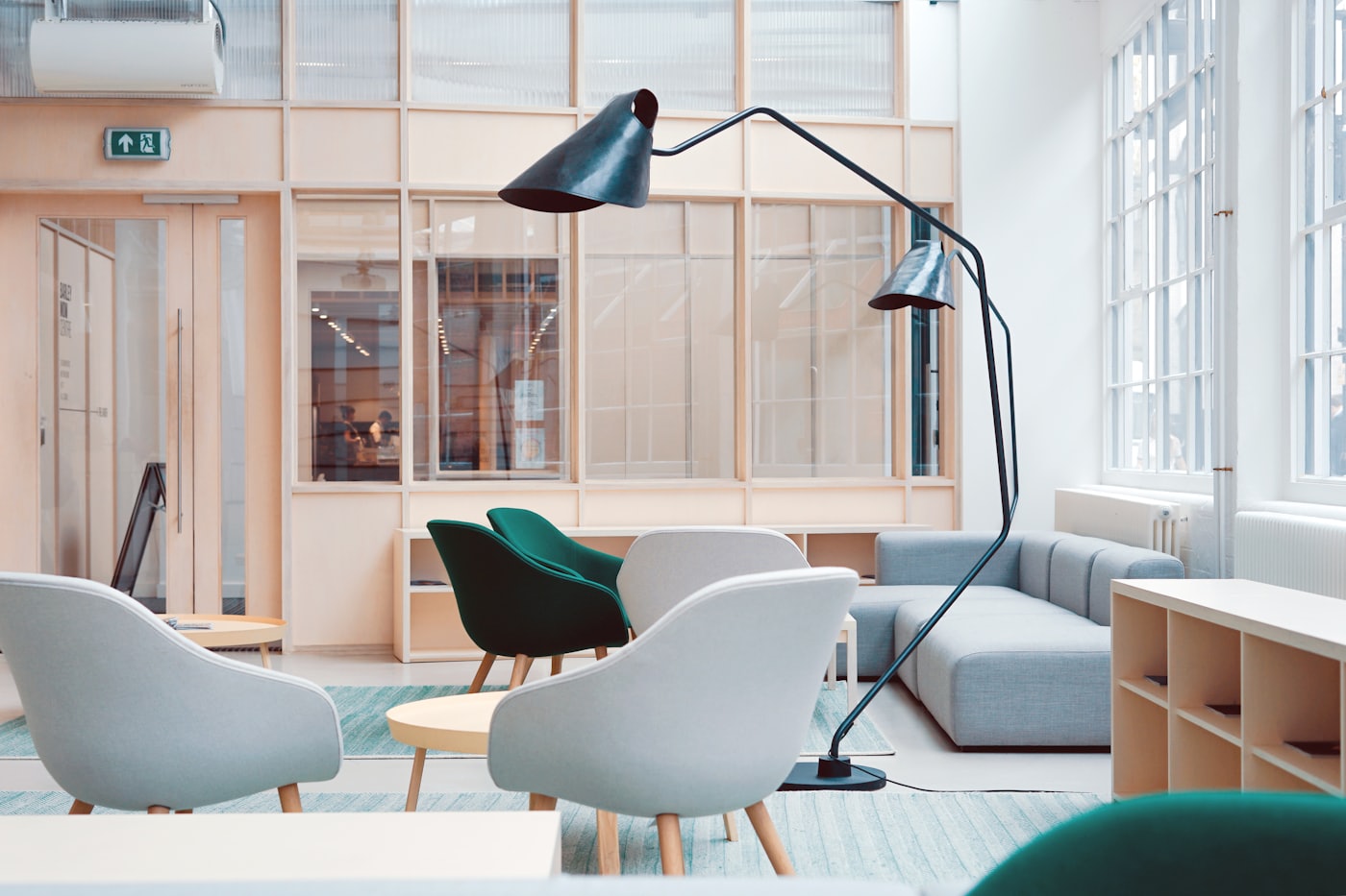 The open studio lounge, with soft chairs, an arc lamp and tall windows along one wall
