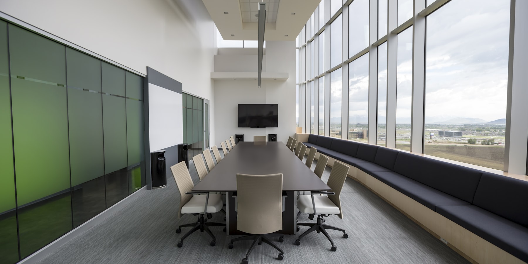 A long boardroom table beside full-height glazing, set for a meeting
